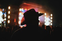 silhouette of a man in a cowboy hat at a concert 