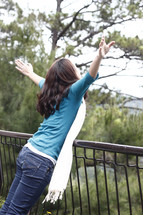 woman pretending to fly leaning over a railing 