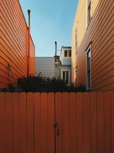 An orange gate between two orange houses.