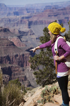 a woman pointing at a ravine from a canyon 