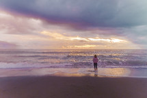 woman standing on a beach at sunset 