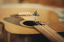 Woman balancing on the strings of a guitar.
