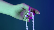 Woman praying and holding mala beads in hand for counts during mantra meditations. Lady on blue background. Spirituality, religion, God concept. High quality photo
