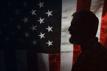 side profile of a bearded man in front of an American flag 