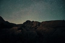Silhouette of a mountain ridge against a star-lit sky.