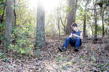 a boy sitting in a forest 