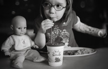 girl child and her doll eating dinner 