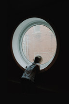 little boy looking out of a porthole window