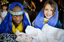 children dressed as Mary, Joseph, and baby Jesus in a live nativity scene 