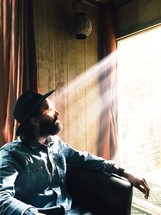 a man sitting in a window with sunlight shining on his face 