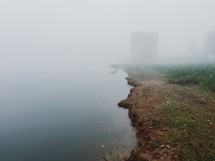 abandoned building in fog near a pond 