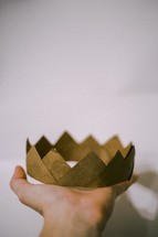 A hand holding a paper crown.