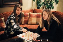 Two young women playing a game of checkers.
