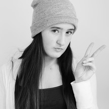 Young girl with stocking cap on giving the peace sign