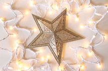 a star Christmas ornament surrounded by Christmas lights 