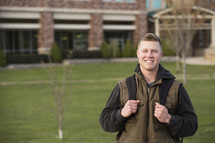 a young man with a book bag on campus 