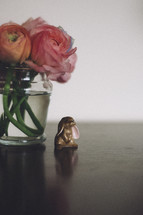 A tiny rabbit figurine sits underneath ranuculus flowers.
