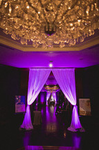 A chandelier hangs from a beautiful reception hall 