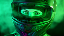 Young female motorcyclist woman in closed motorcycle helmet. Driver biker looking to camera under colorful neon light. Amazing aesthetic portrait. High quality photo
