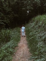 boy child standing on a dirt path 