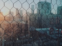 blurry view of a city through chicken wire 