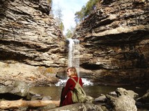 Hiker resting on a rock near a waterfall.