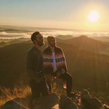 two men standing on top of a mountain under sunlight
