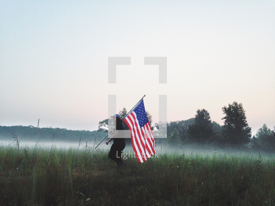 man with an American flag in a field 