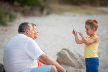 Boy taking phone photo of grandparents outdoor