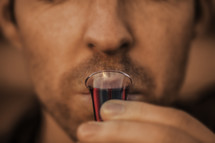 closeup of a man drinking wine from a communion cup 