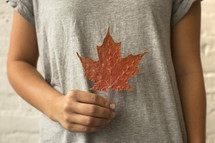 a child holding a fall leaf 