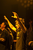 A young man with hands raised in worship.