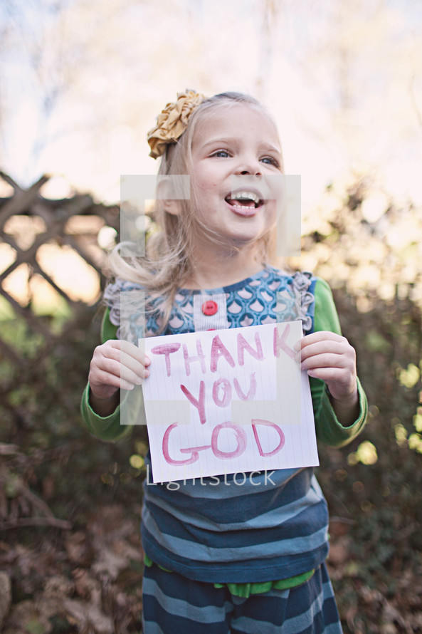 girl holding a sign that says "Thank You God" 