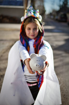 a child dressed as a king holding a piggy bank 