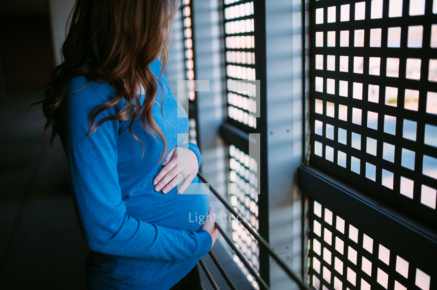pregnant woman looking out a window 