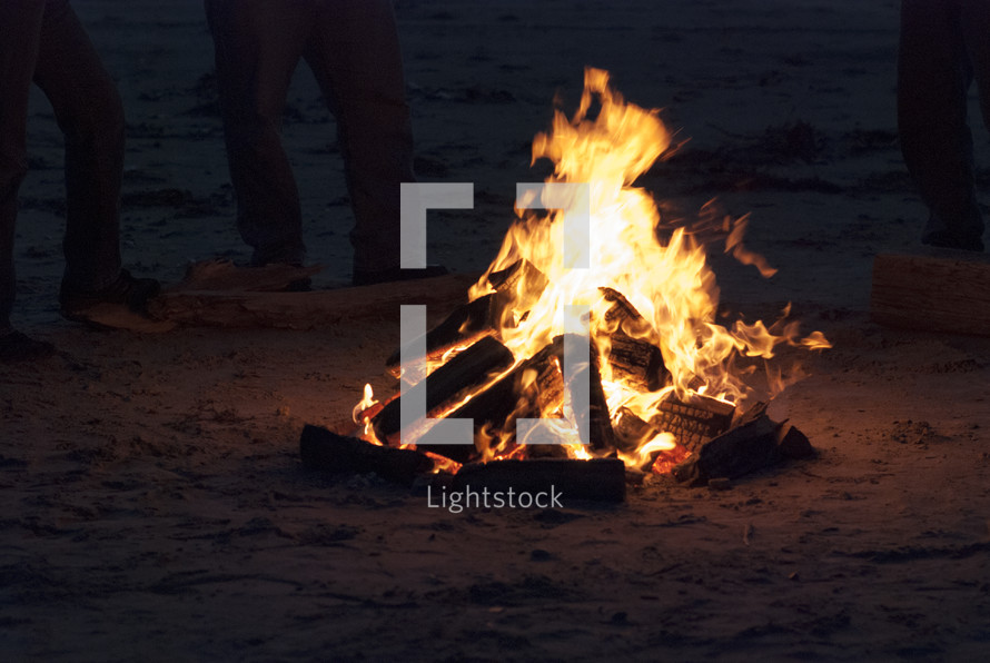 standing around a bonfire on a beach 