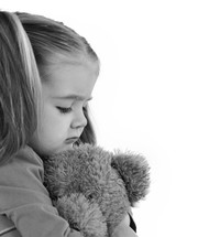sad little girl holding a teddy bear 