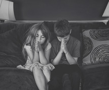 children praying on a couch at home 