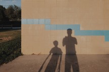 shadows of a father and son on a wall 