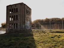 An old abandoned brick building surrounded by fencing.