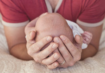 A father cradling an infant in his hands. 