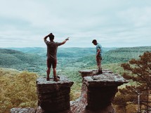 men standing on rocks at the top of a mountain 