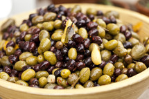 Bowl of black and green olives with garlic cloves and bay leaves.