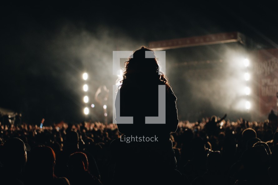 silhouette of a woman standing at a concert 
