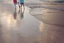 family walking on wet sand on a beach 