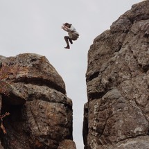man leaping across a steep ravine 