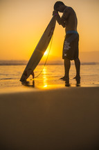 surfer with head bowed over his surfboard in prayer