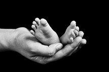 a mother's hand holding infant feet 
