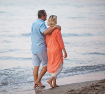 Senior couple enjoying barefoot walk at the seaside