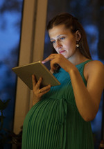 Serious pregnant woman using tablet at home
